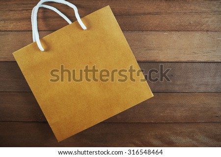 Blank brown shopping bag on wooden background. 