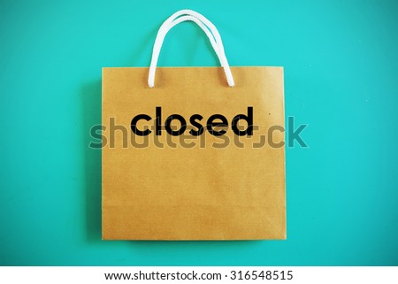 Closed sign on brown shopping bag on mint green background. 