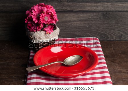 Empty red plate on wooden table over wooden background