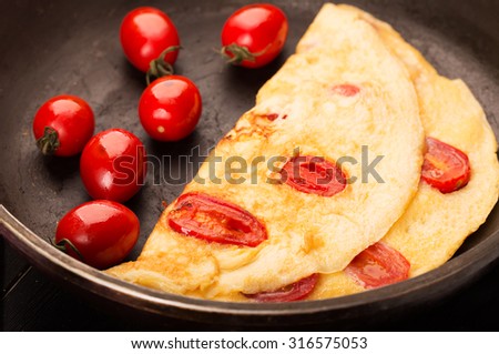 Omelette with cherry tomatoes on the black pen