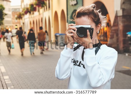 Young woman with camera photographing at the street