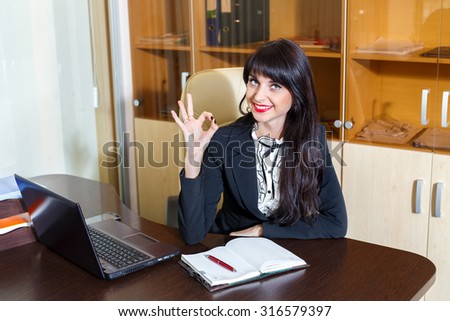 Nice smiling woman in office showing okay symbol