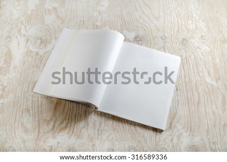 Photo of blank opened brochure magazine on light wooden background with soft shadows. Mock-up for graphic designers portfolios.