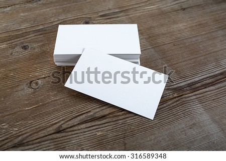 Photo of blank business cards with soft shadows on dark wooden background. For design presentations and portfolios.