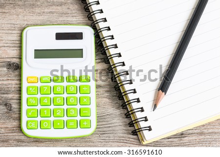 Calculator with Notebook and Pencil on Wood Background