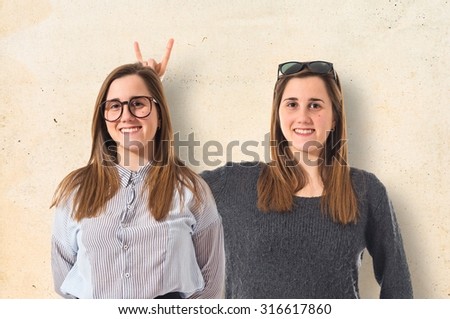 Girl teasing her sister over textured background