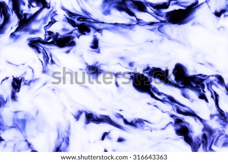Blue ink flowing and mixing in milk texture.