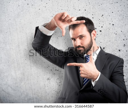 Young businessman doing a frame sign over textured background