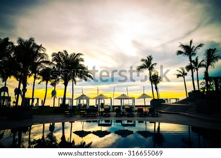 Silhouette palm tree with umbrella chair pool in luxury hotel resort at sunrise times  - Vintage filter effect processing style pictures
