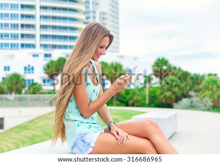 pretty teenager sitting in the park and using mobile phone