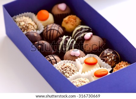 Handmade chocolate candies into the blue gift box on the white background