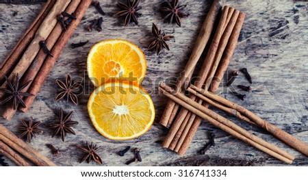 Artistic closeup of orange, cinnamon and star anise seeds on a wooden background. Sunny still life photo. Holiday spices.  