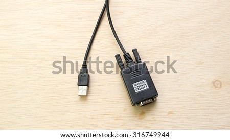 Black color usb to 9 pin RS-232 serial port cable converter adapter on wooden surface. Slightly de-focused and close-up shot. Copy space.