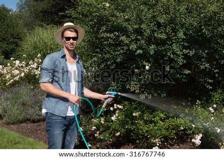 young handsome man is watering the plants
