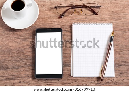 Notebook with pen, smart phone and coffee cup on wooden table