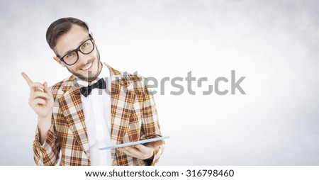 Geeky hipster holding a tablet pc against white wall