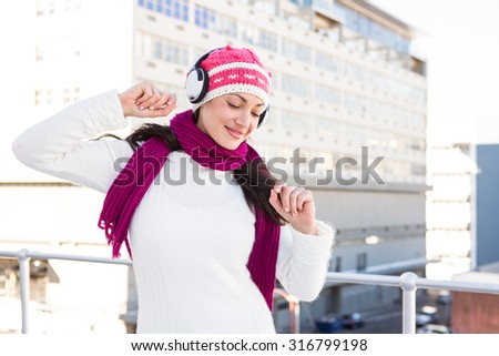 Happy woman listening to headphones outside