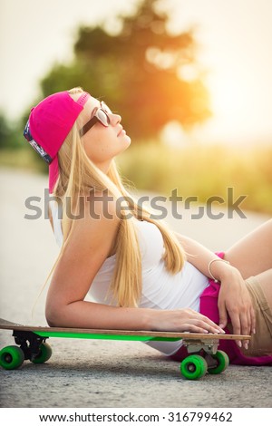 Attractive hipster teenage girl with skateboard, image with sunflare