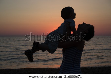 Mother and son at sunset on the sea
