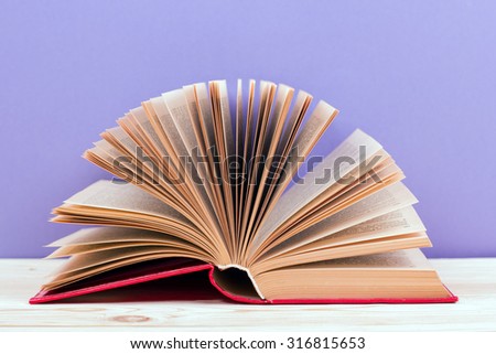 Composition with vintage old hardback books, diary, fanned pages on wooden deck table and purple background. Books stacking. Back to school. Copy Space. Education background
