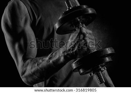 man with dumbbell flexing biceps over concrete wall background
