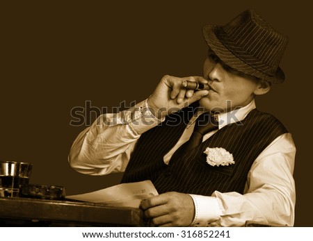 young gangster with hat smoking cigar, studio shot, sepia toning