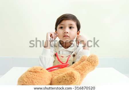 Asian boy play with bear  in the room.
