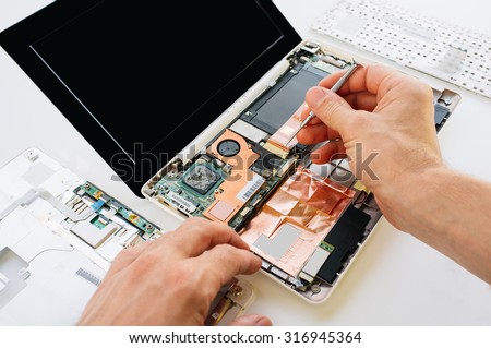 The engineer repairs the laptop (pc, computer) and the motherboard. Installs the equipment (cpu) Royalty-Free Stock Photo #316945364