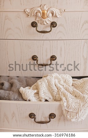 Open white vintage wardrobe. Wool sweaters in closet. Winter mood