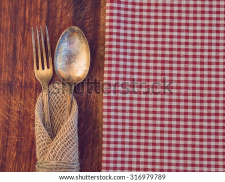 Vintage toned picture of the fork and spoon lying at the old table.