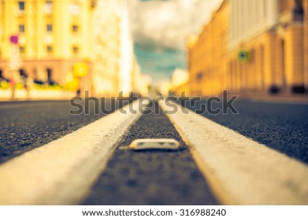 Clear day in the big city, empty city street under sunlight. View of the road at the level of the dividing line, image in the yellow-blue toning