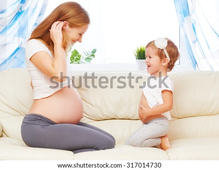 happy family. Pregnant mother and child daughter having fun relaxing and playing on the sofa at home
