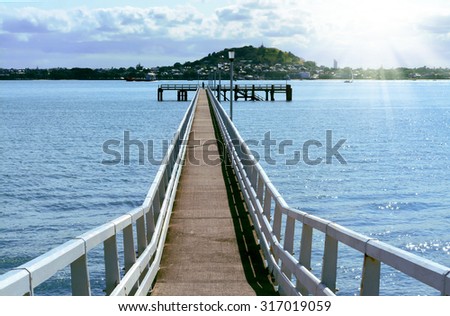Lond pier into sea with mountains in the background