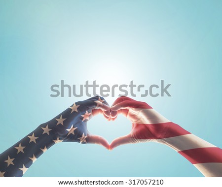 United States of America -USA American flag pattern on people hands in heart love shape isolated on blue sky background 