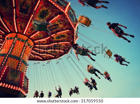  a swinging fair ride at dusk toned with a retro vintage instagram filter app or action with motion blur and grainy effect added for a grunge look and feel  Royalty-Free Stock Photo #317059550