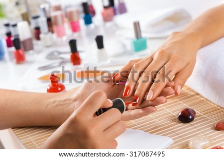Woman in salon receiving manicure by nail beautician Royalty-Free Stock Photo #317087495