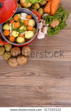 Casserole dish or stew pot, vegetables and herbs, copy space.