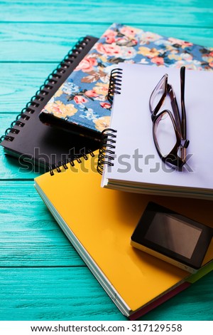 Notebooks and glasses on blue wooden table. Vertical workspace and selective focus.