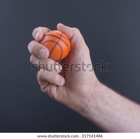 Isolated hand with a mini basket ball on a black background