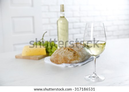 Still life of wine, grape, cheese and bread on light background
