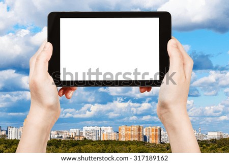 travel concept - hand holds tablet pc with cut out screen and skyline with blue clouds on background