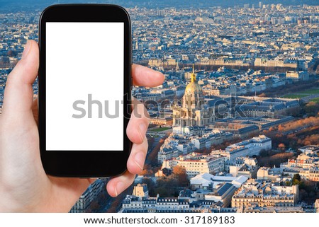 travel concept - hand holds smartphone with cut out screen and Paris cityscape on background