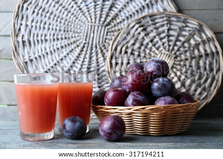 Delicious plum juice with fruits on wicker background