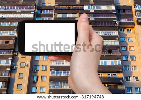 travel concept - hand holds smartphone with cut out screen and facade on apartment house in Moscow on background