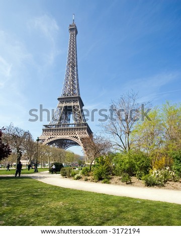 Color DSLR image of landmark tourist attraction Eiffel Tower, Paris, France, in Springtime with a green grass lawn foreground clear blue sky background. Vertical with copy space for text.