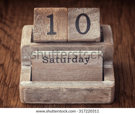 Grunge calendar showing Saturday the tenth on wood background