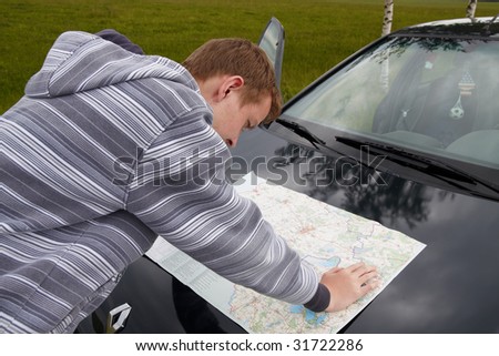 The lost road. The young guy searches for road on a  map