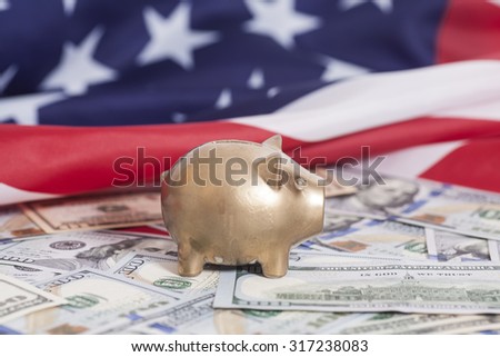 Golden Piggy Bank on Dollars with American Flag Royalty-Free Stock Photo #317238083