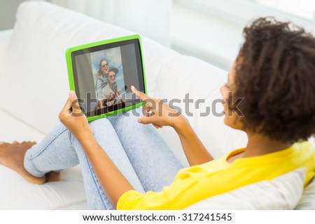 people, technology, advertisement and leisure concept - happy african american young woman sitting on sofa and looking at picture on tablet pc computer screen at home
