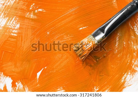 Painting brush and orange paint as a background